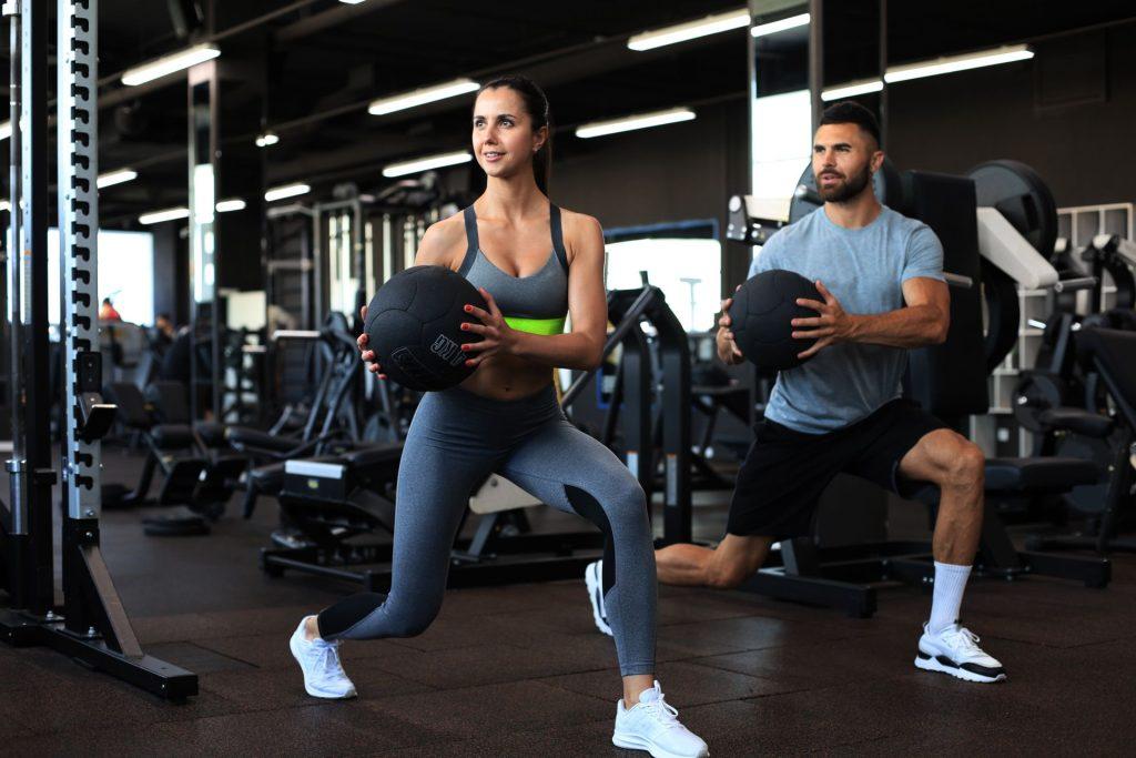Man and woman in the gym performing a workout using a medicine ball